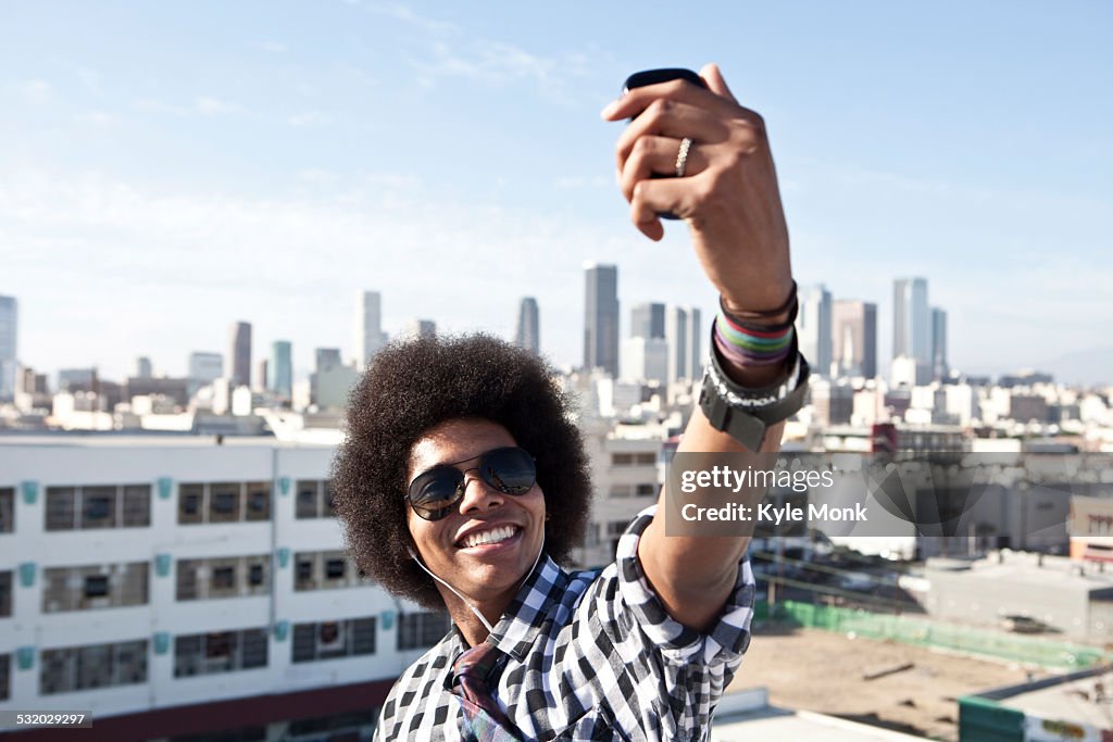 African American man taking cell phone picture from urban rooftop