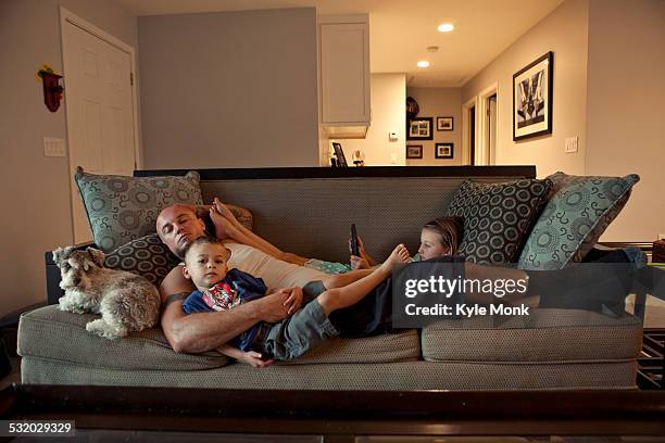 caucasian father and children relaxing on sofa - family on couch stock pictures, royalty-free photos & images