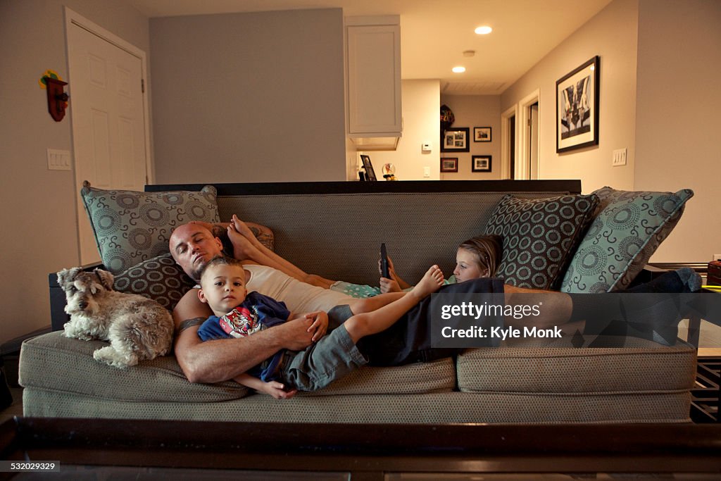 Caucasian father and children relaxing on sofa