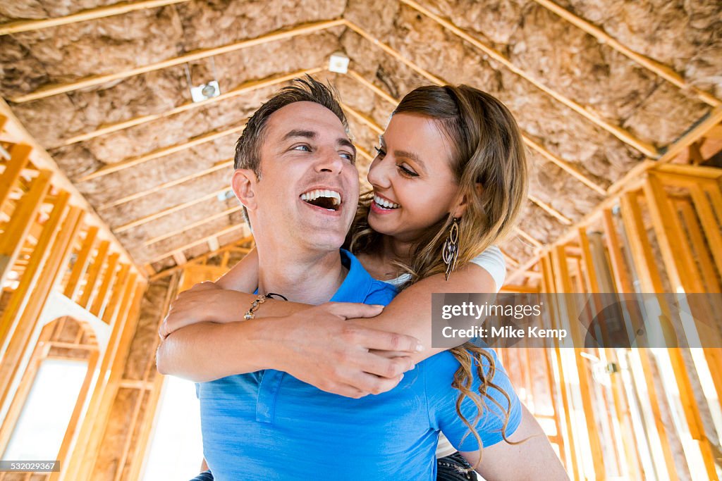 Caucasian couple hugging in house under construction