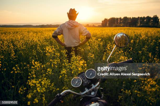 Mari man standing near motorcycle in field of flowers