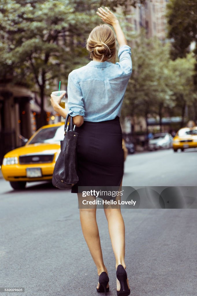 Caucasian woman hailing taxi in urban street