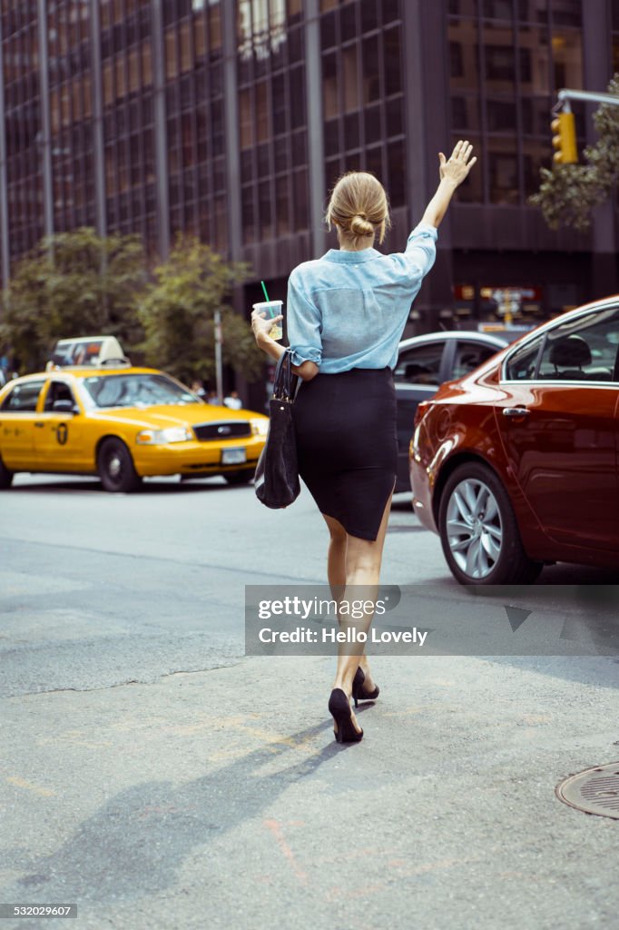 Caucasian woman hailing taxi in urban street