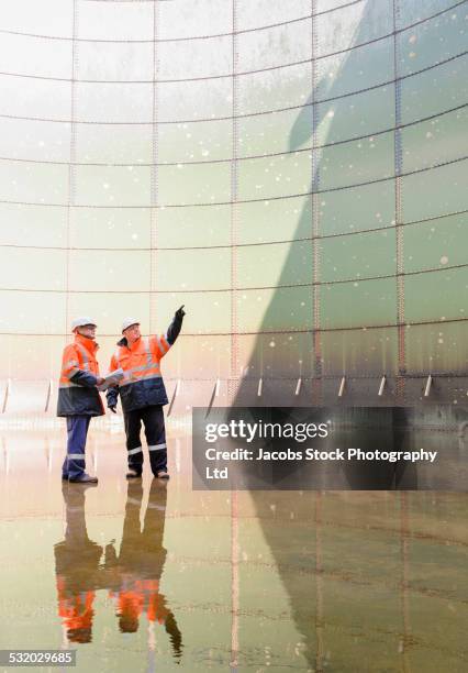caucasian technicians examining fuel storage tank - gas engineer stockfoto's en -beelden