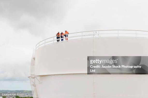 caucasian technicians standing on fuel storage tank - marine engineering stock pictures, royalty-free photos & images