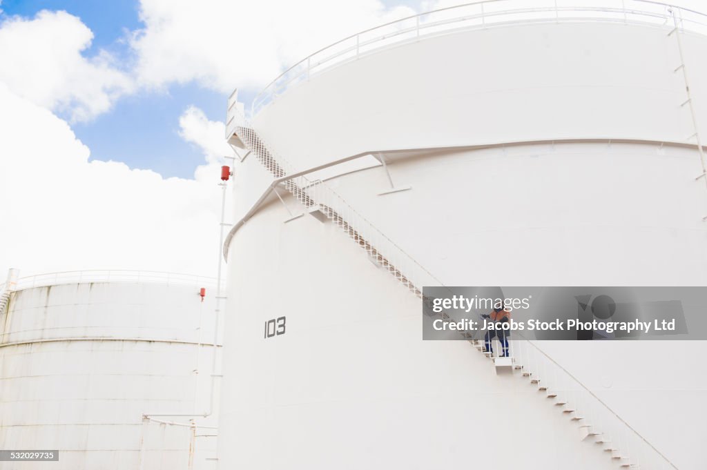 Caucasian technician standing on fuel storage tank staircase
