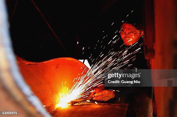 Labourer works at a boatyard in Ganlanba Dock along the Lancang-Mekong River on July 6, 2005 in Xishuangbanna Prefecture, Yunnan Province, China. The...
