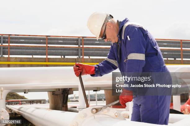 caucasian technician tightening bolts on pipe - tighten - fotografias e filmes do acervo