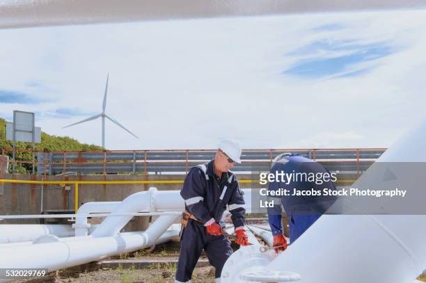 caucasian technicians tightening bolts on pipe - senior blaumann stock-fotos und bilder