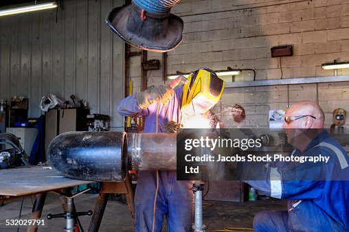 Caucasian welders working on pipe in workshop