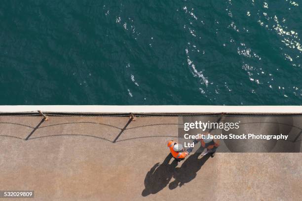 overhead view of caucasian technicians shaking hands near water - partnership handshake stock pictures, royalty-free photos & images