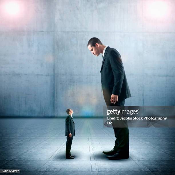 businessman looking down on miniature colleague - big small stock-fotos und bilder