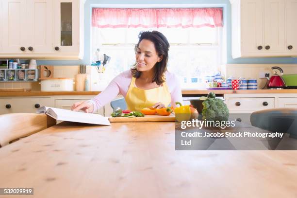 hispanic woman cooking with vegetables at kitchen table - surface preparation stock pictures, royalty-free photos & images