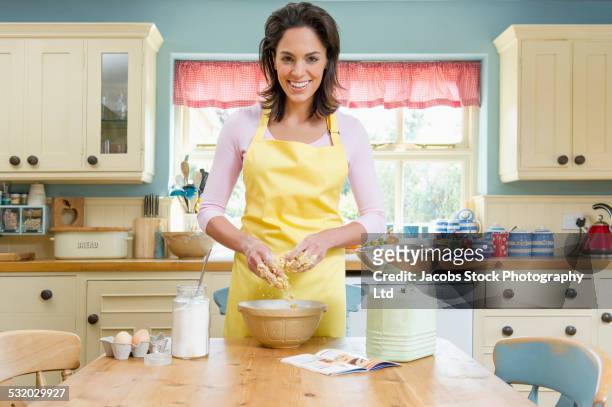 hispanic woman baking at kitchen table - hausfrau stock-fotos und bilder