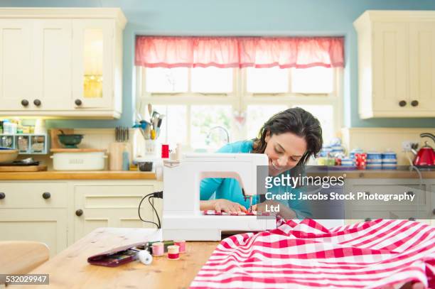 hispanic woman using sewing machine on kitchen table - sewing machine imagens e fotografias de stock