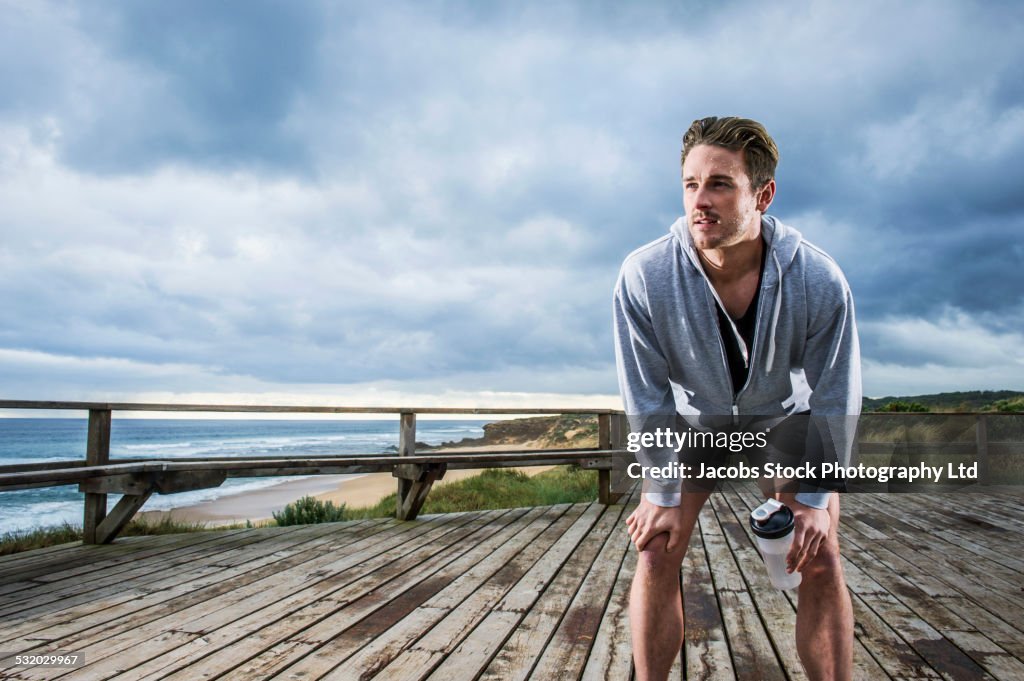 Caucasian runner resting on wooden boardwalk at beach
