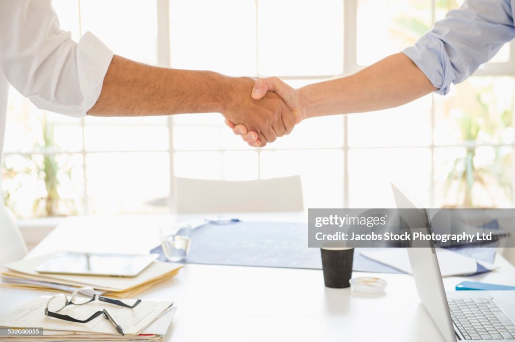 Business people shaking hands over conference table