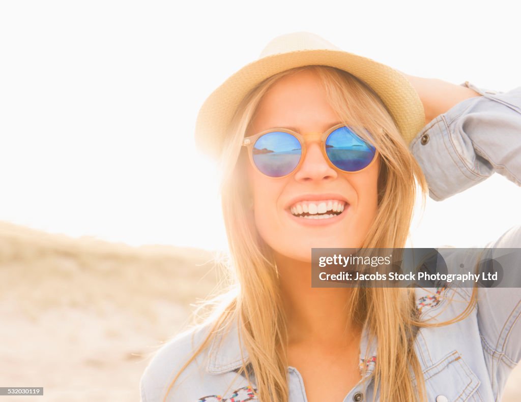 Caucasian woman wearing hat and sunglasses on beach