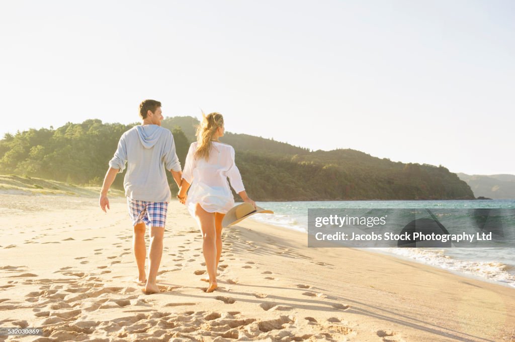 Caucasian couple walking on beach