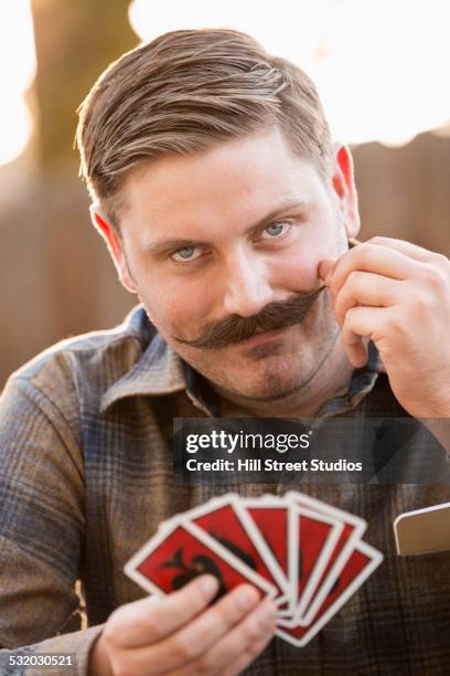 man twirling his mustache during card game - vilão - fotografias e filmes do acervo