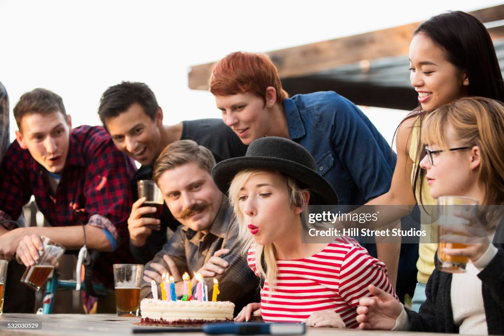 Woman blowing out candles on birthday cake at party