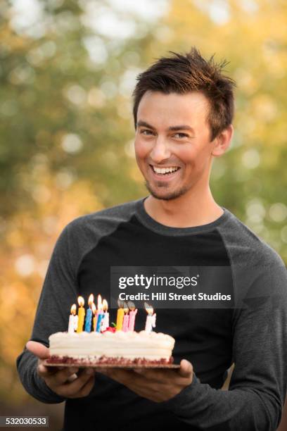 pacific islander man holding birthday cake at party - holding birthday cake stock pictures, royalty-free photos & images