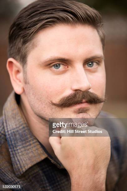 man resting chin in hand outdoors - man with moustache stock-fotos und bilder