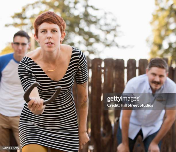 woman throwing horseshoe in game outdoors - three horseshoes stock pictures, royalty-free photos & images