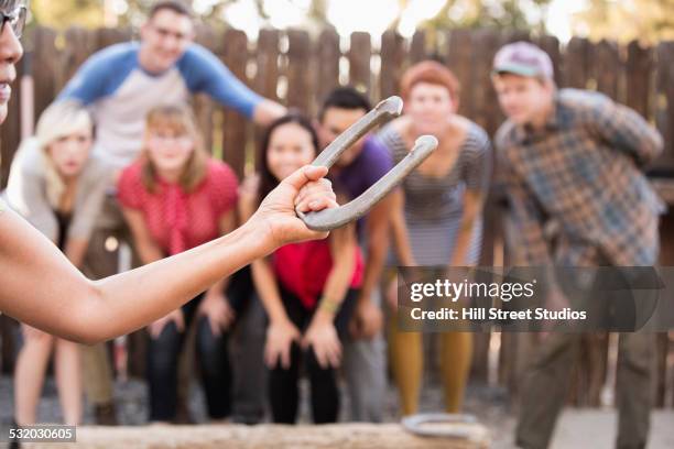 friends watching woman play horseshoe in backyard - horseshoes stockfoto's en -beelden