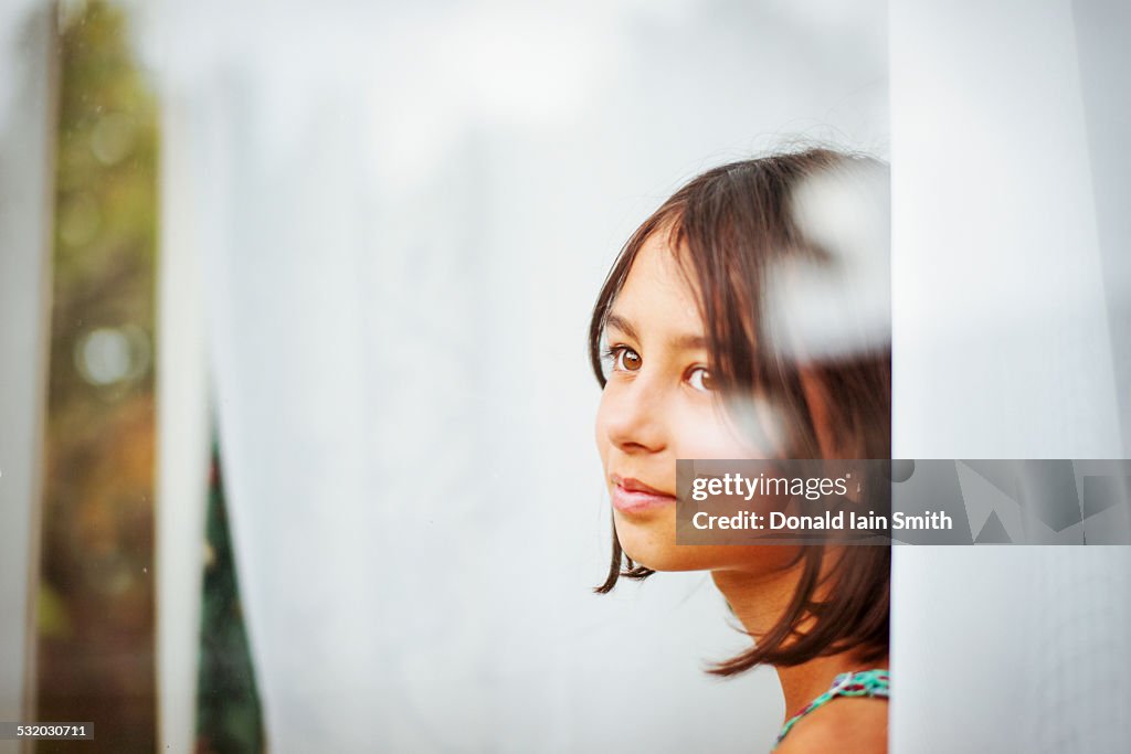 Mixed race girl standing near window