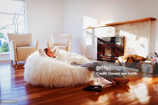 mixed race girl relaxing in beanbag chair in living room - bean bags fotografías e imágenes de stock