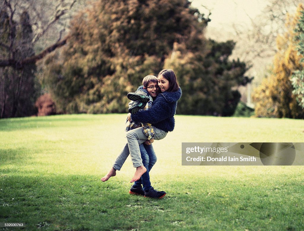 Mixed race brother and sister playing in field