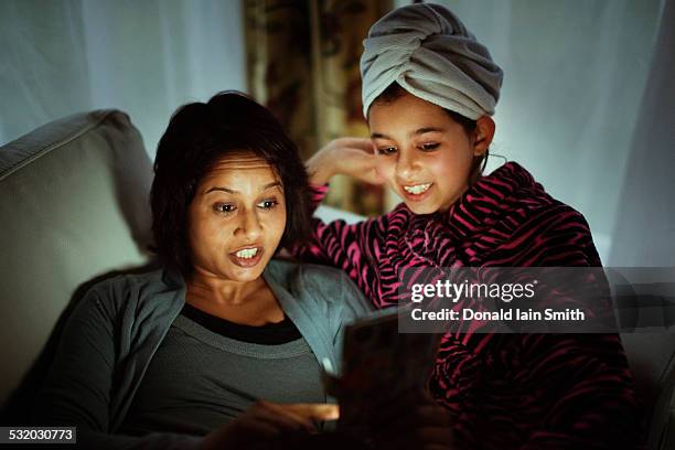 mixed race mother and daughter using digital tablet at night - 11 year old indian girl stock pictures, royalty-free photos & images