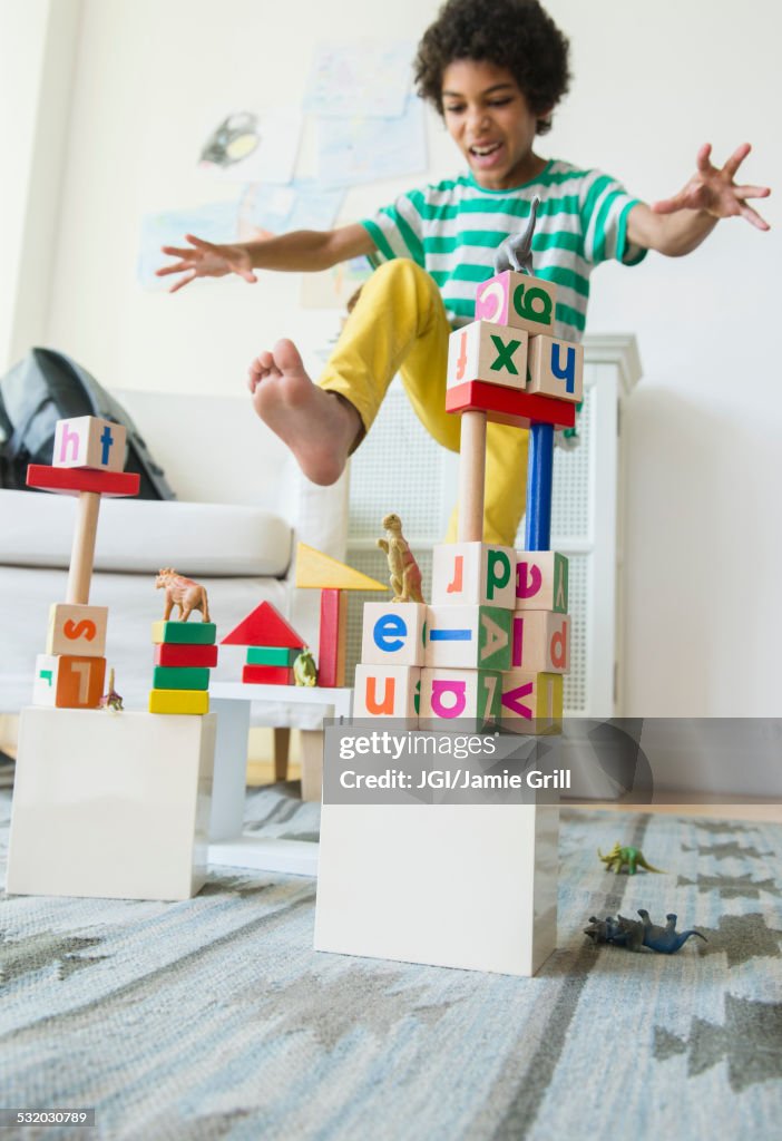 Mixed race boy wrecking wooden block city in living room