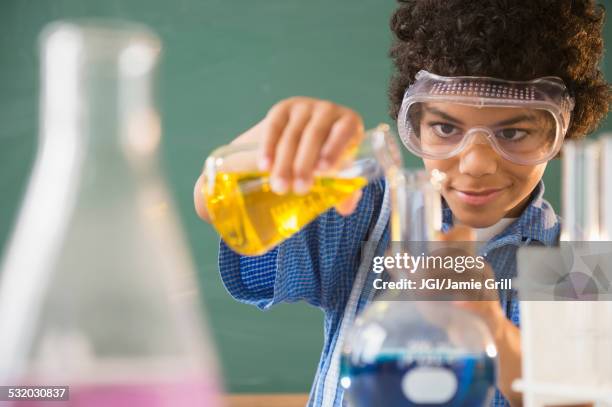 mixed race boy experimenting in classroom science lab - science lab school stock-fotos und bilder