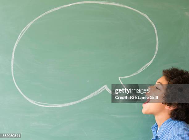 mixed race boy shouting into speech bubble on chalkboard - kids speech cartoon stock pictures, royalty-free photos & images