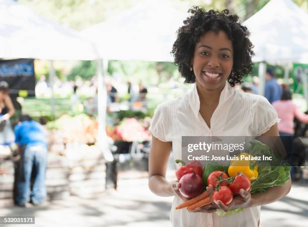african american woman holding produce at farmers market - west new york new jersey stock-fotos und bilder