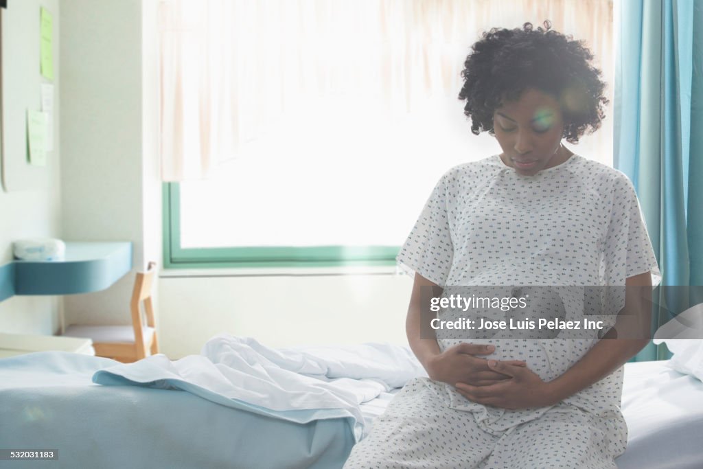 Pregnant African American woman holding her stomach in hospital