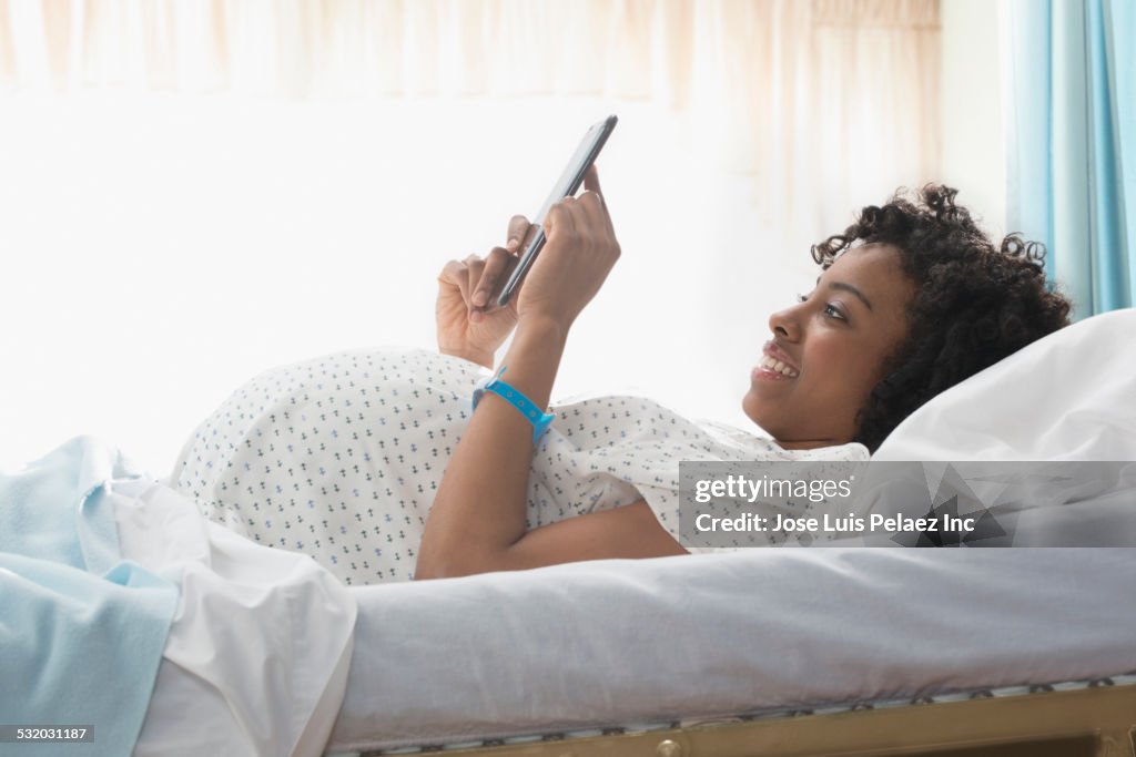 Pregnant African American woman using digital tablet in hospital