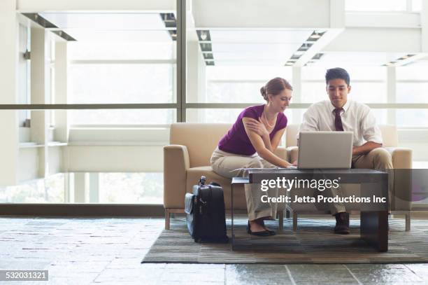 business people using laptop in office lobby - formal businesswear stock pictures, royalty-free photos & images