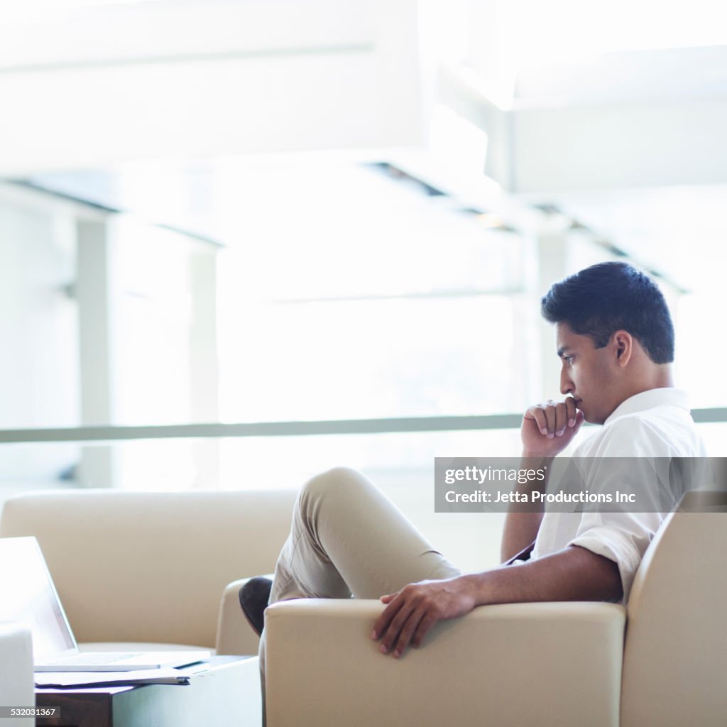 Indian businessman using laptop in office lobby