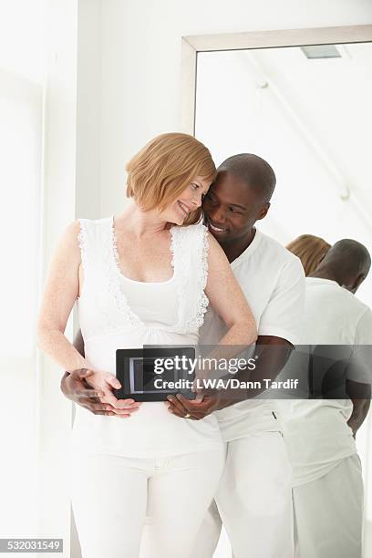 boyfriend holding sonogram over stomach of pregnant girlfriend - interracial wife photos stock-fotos und bilder