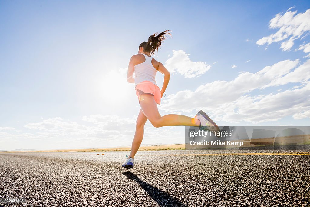 Low angle view of Caucasian woman running on remote road