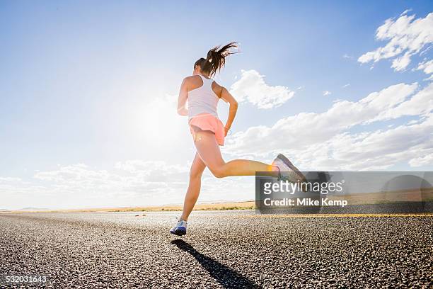 low angle view of caucasian woman running on remote road - back shot position stock pictures, royalty-free photos & images