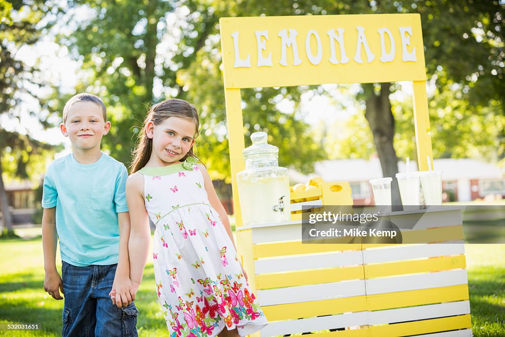 Caucasian brother and sister smiling at lemonade stand