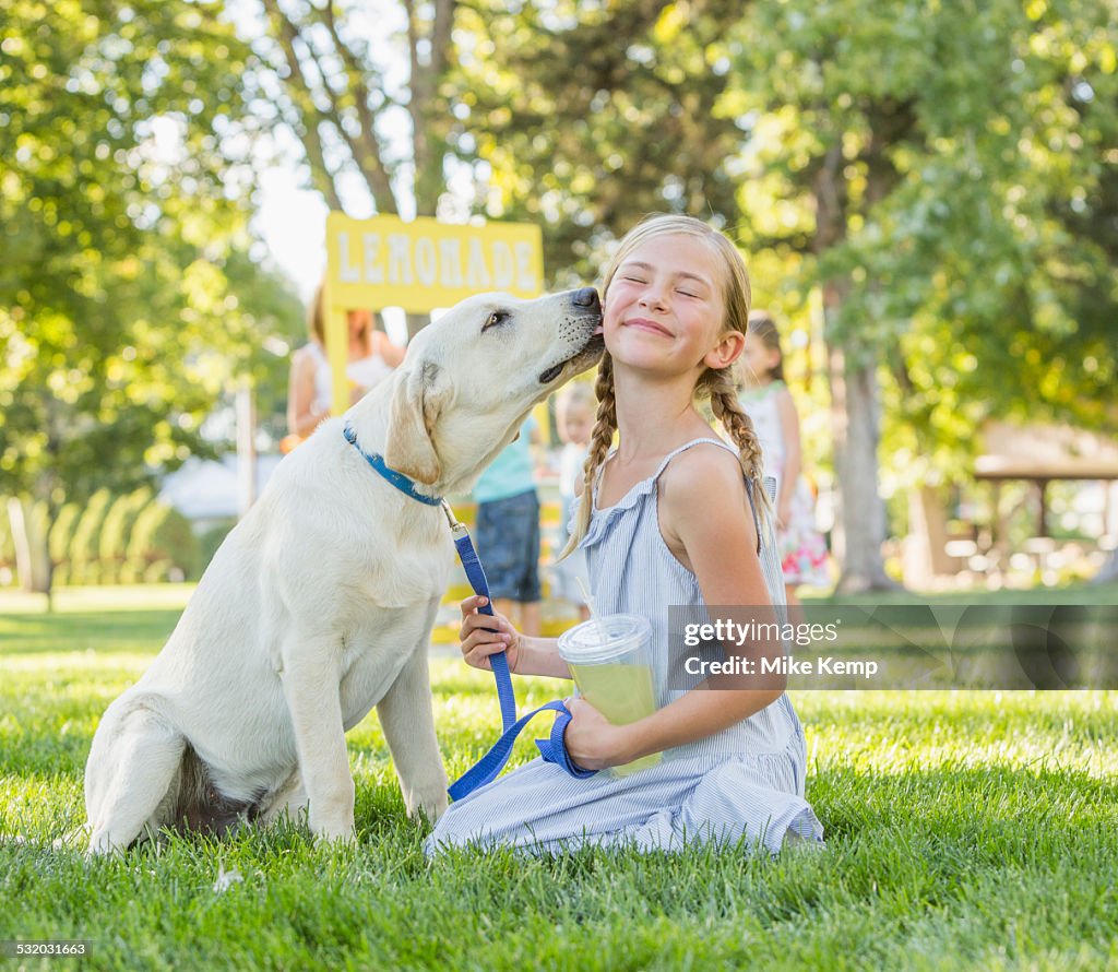 Pet dog licking face of Caucasian girl on grassy lawn