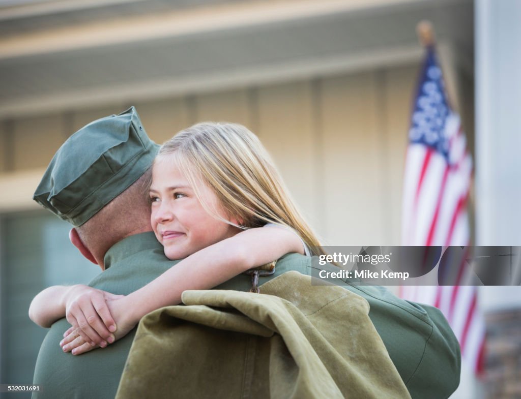 Returning Caucasian soldier hugging daughter