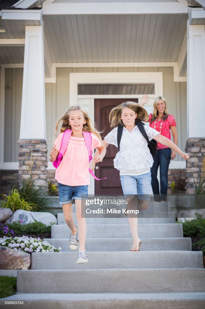 Caucasian mother sending running sisters to school