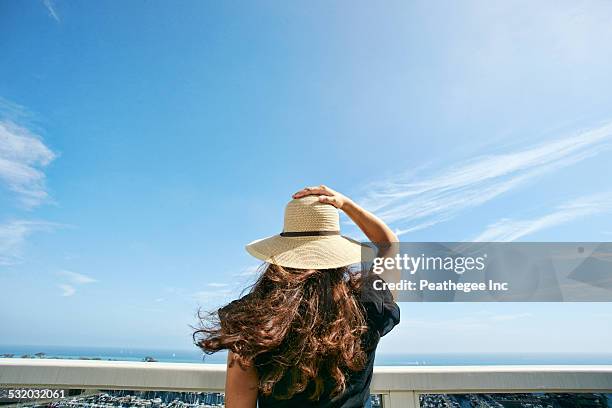 woman in sun hat admiring scenic view from balcony - beach hat stock pictures, royalty-free photos & images
