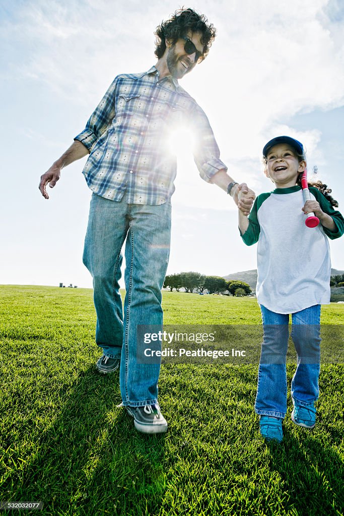 Father and daughter walking in grassy field